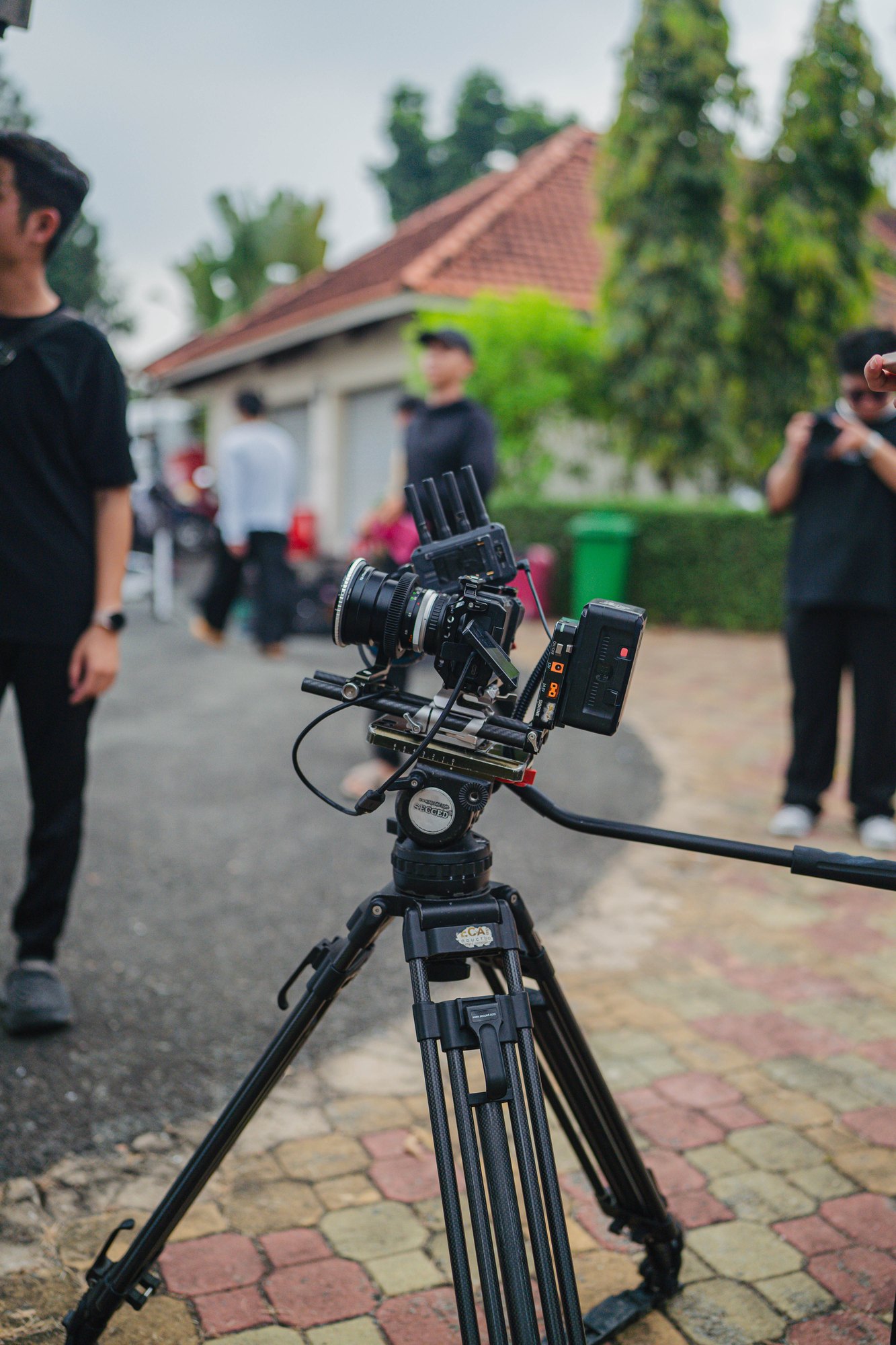 Cinema camera rig on sticks with crew working behind